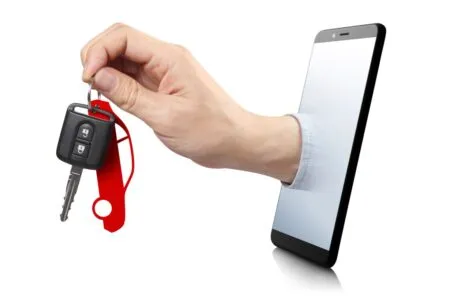 Hand reaching through a smartphone screen offering car keys with a red keychain